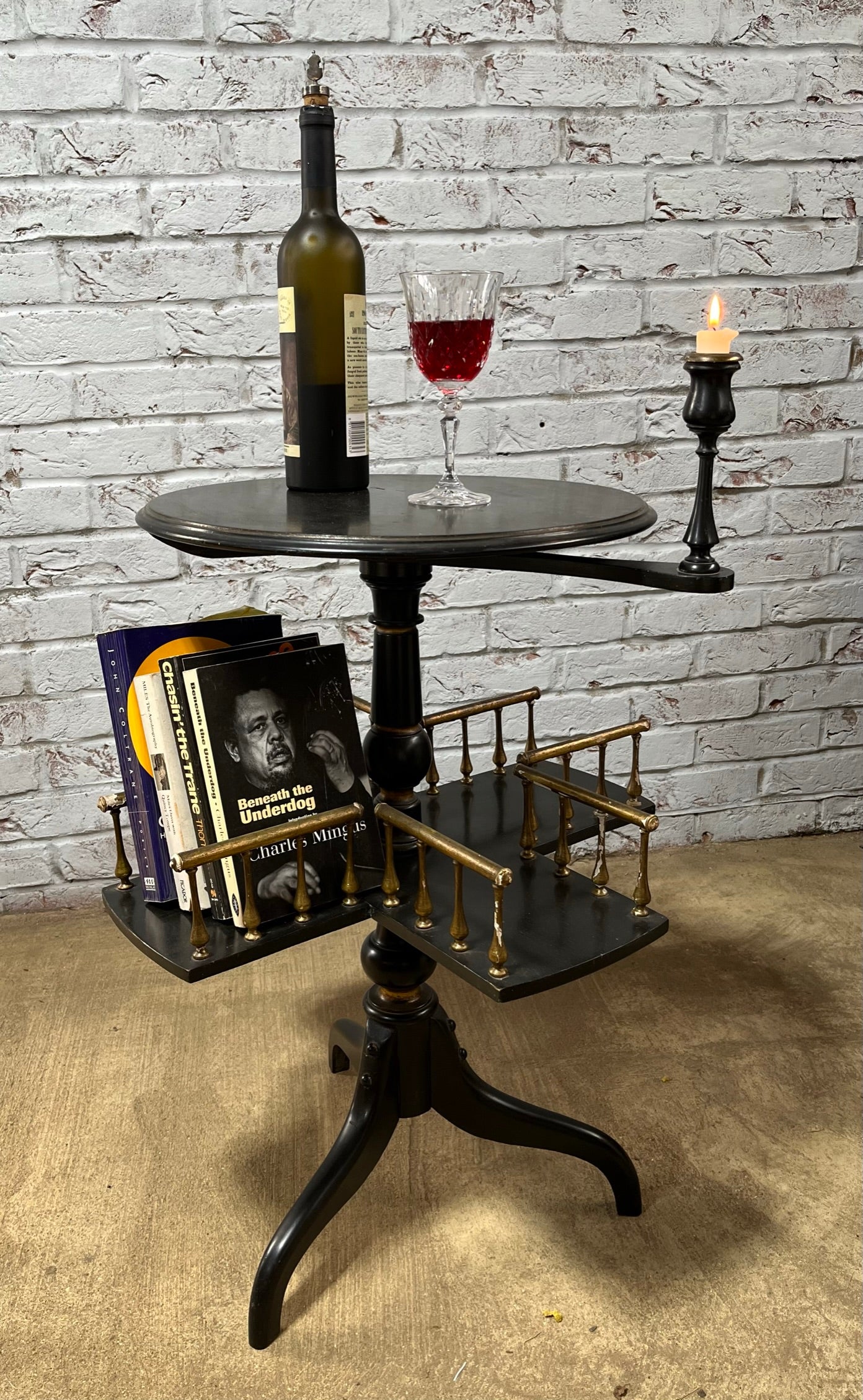 Ebonised and gilt revolving book table with candle holder.