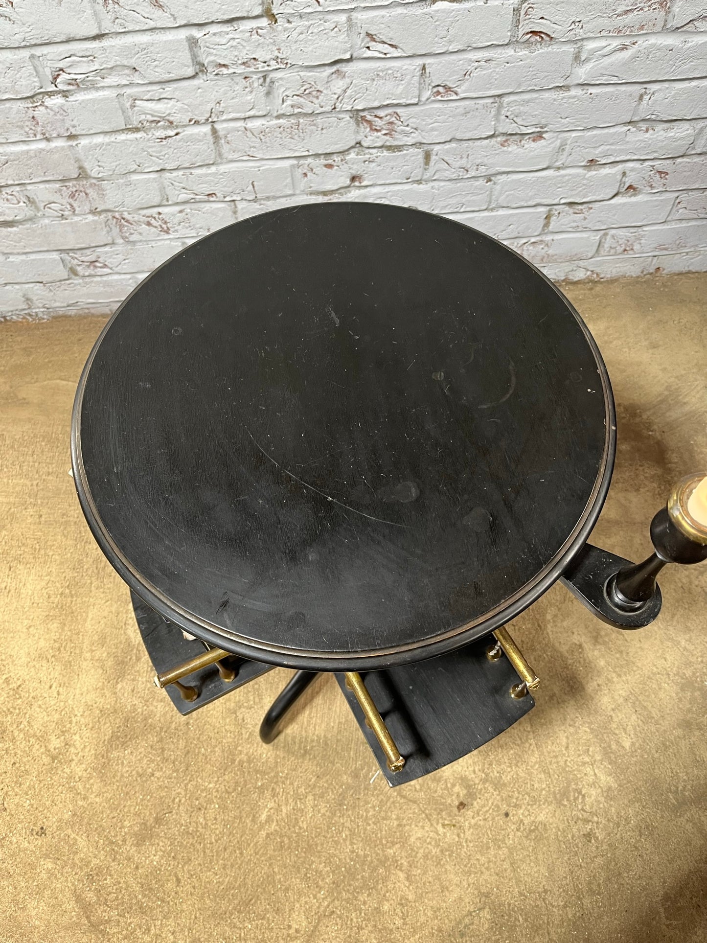 Ebonised and gilt revolving book table with candle holder.