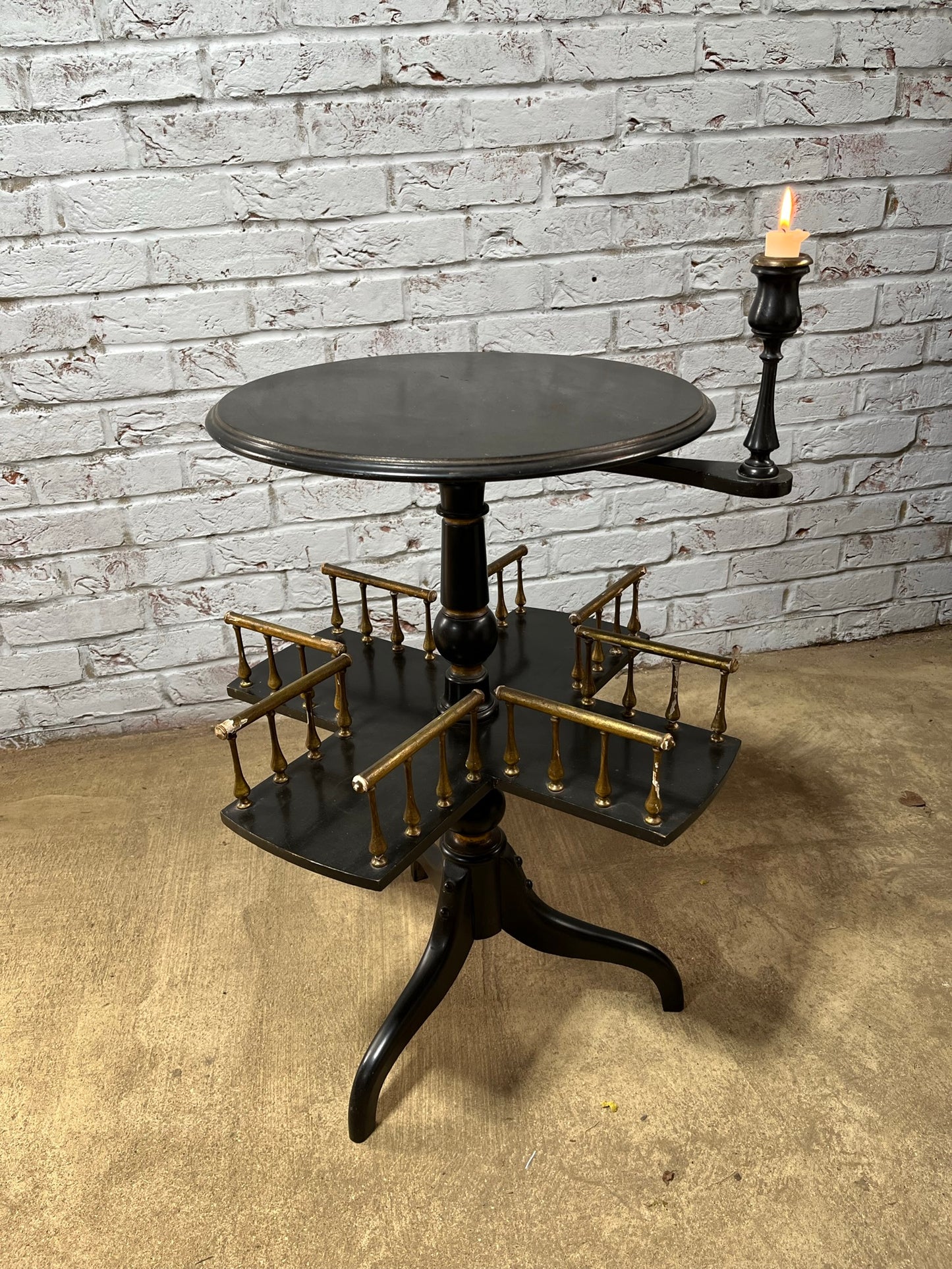 Ebonised and gilt revolving book table with candle holder.