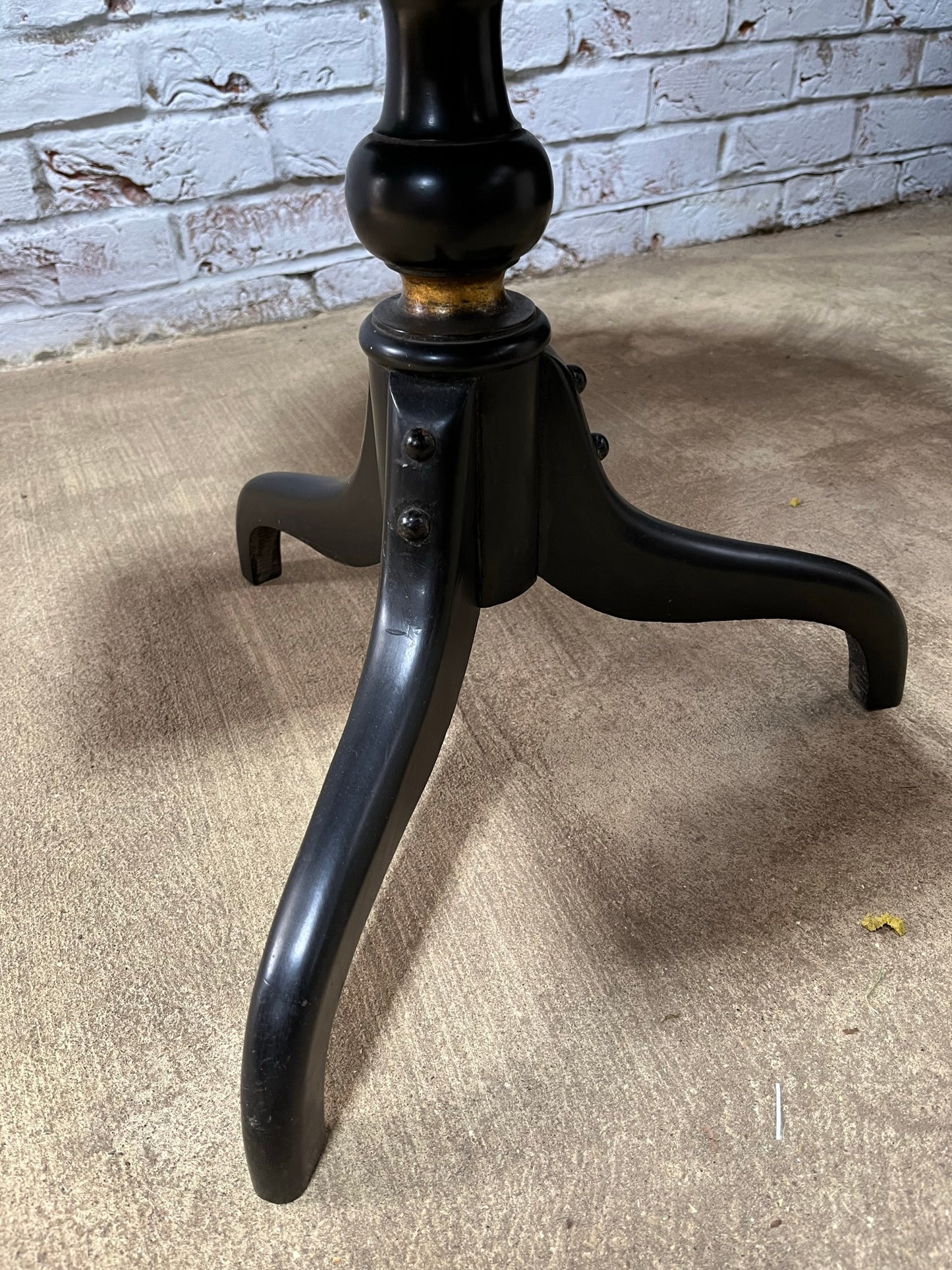 Ebonised and gilt revolving book table with candle holder.